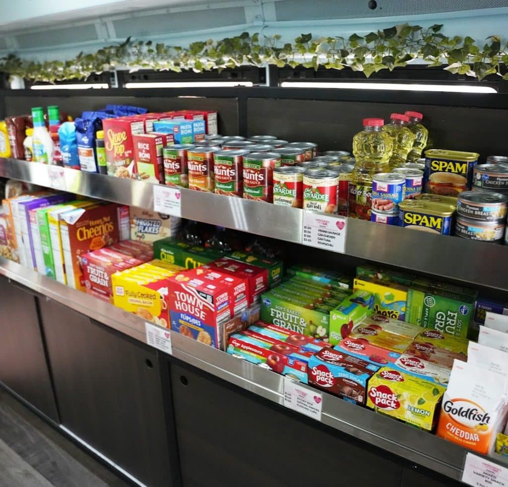 A well-stocked food pantry with shelves of canned goods, cereal, snacks, and cooking oil.