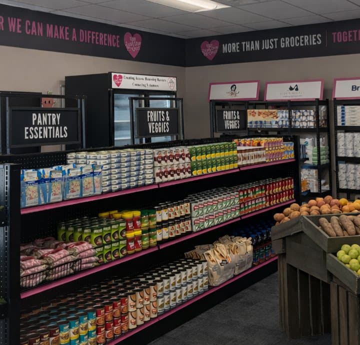 A grocery store aisle with shelves of canned goods, boxed items, and fresh produce.